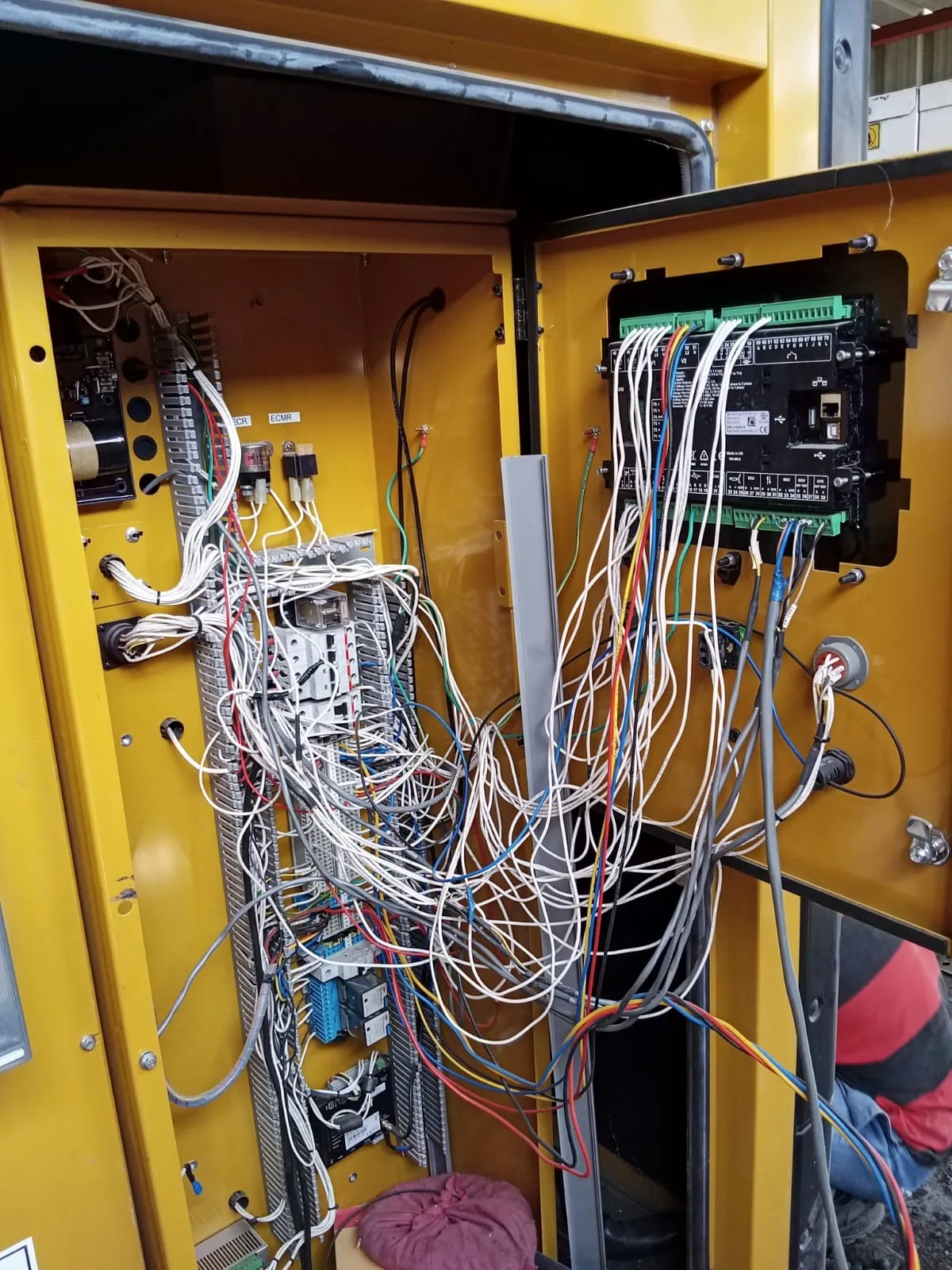 Generator control cabinet open mid-job with a new controller wired on the door