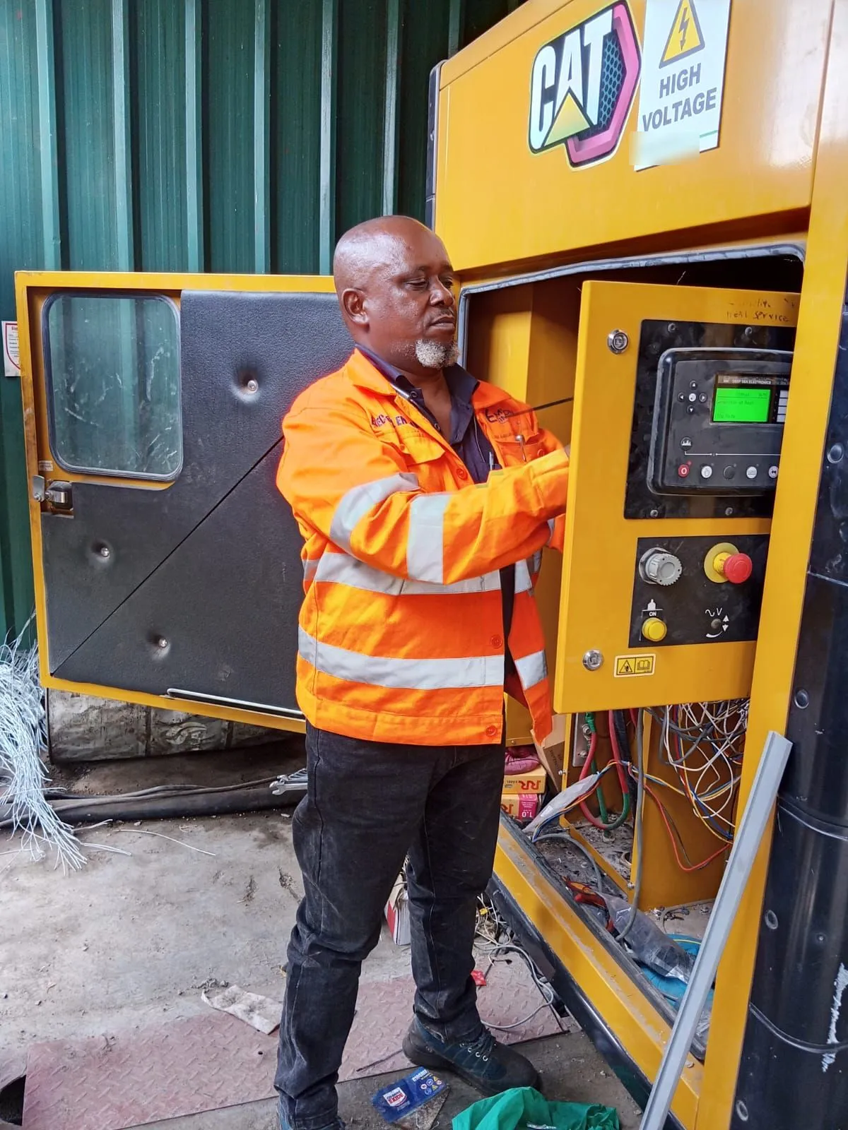 EmersonEIMS engineer in branded hi-vis at the control panel of a CAT generator