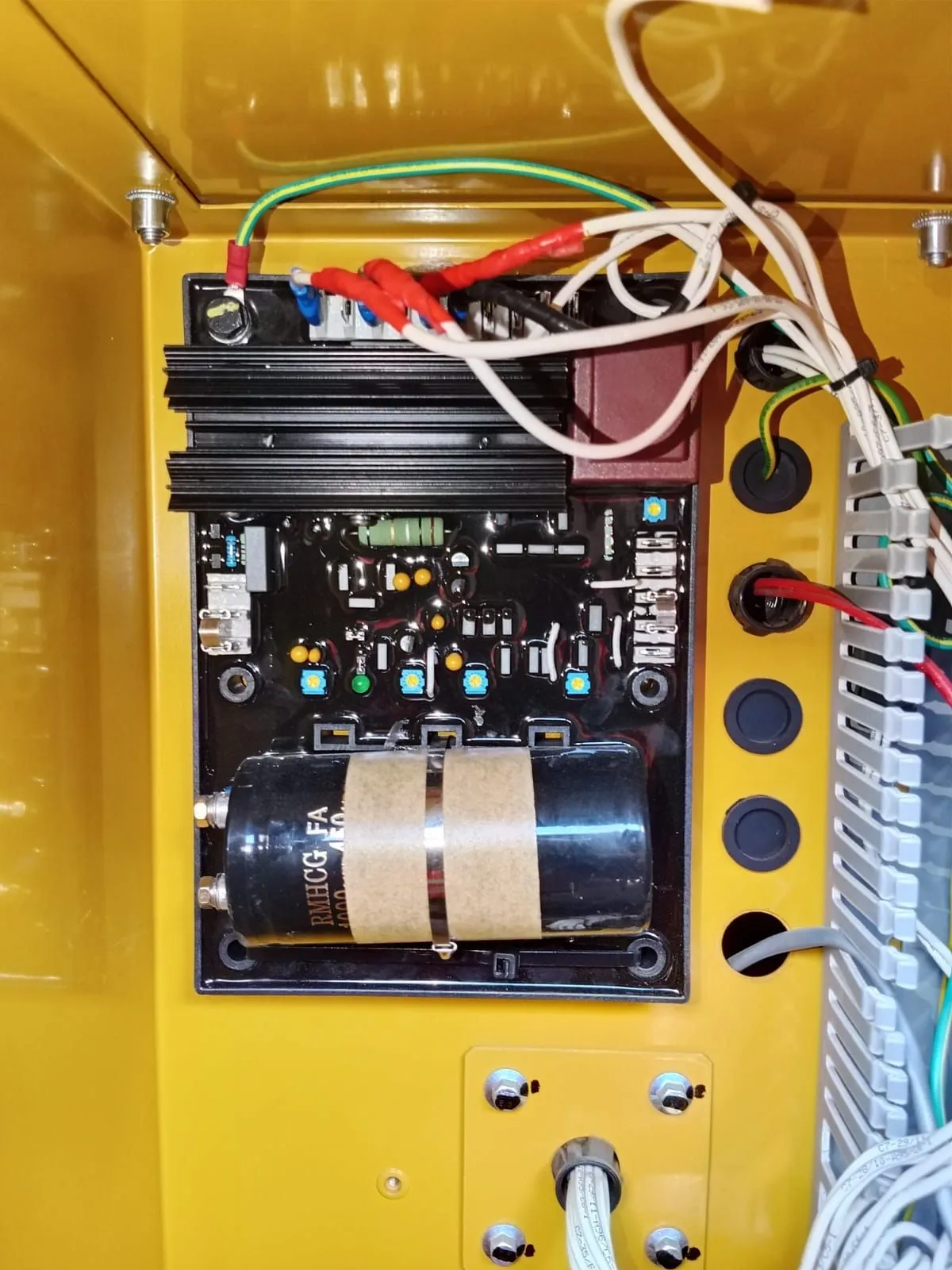 Automatic voltage regulator board with capacitor inside a generator terminal box