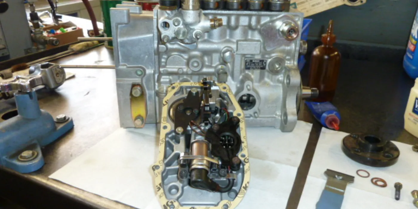 Bosch inline injection pump on the rebuild bench with the governor cover removed, showing the internal governor mechanism and a new gasket